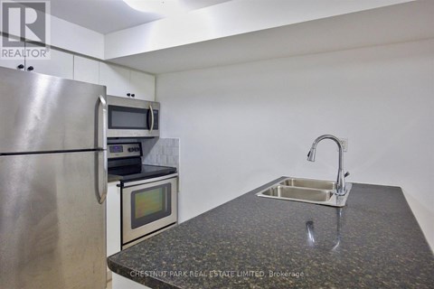 A kitchen with a granite countertop and stainless steel appliances.