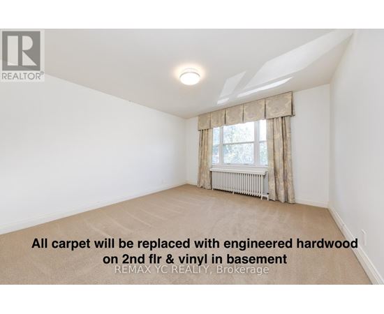 A room with a window and a carpet that will be replaced with engineered hardwood.