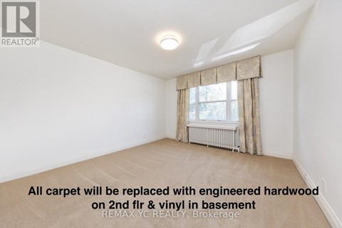 A room with a window and a carpet that will be replaced with engineered hardwood.