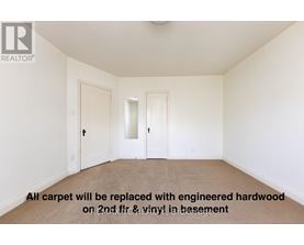 A room with a carpeted floor and a note that says all carpet will be replaced with hardwood.