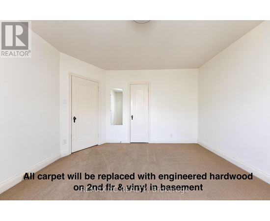 A room with a carpeted floor and a note that says all carpet will be replaced with hardwood.