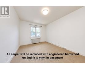 A room with a window and a radiator, with a note on the floor.