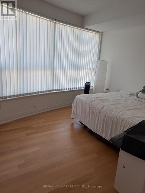A bedroom with a bed, nightstand, and window with blinds.