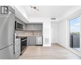 A modern kitchen with stainless steel appliances and wooden flooring.