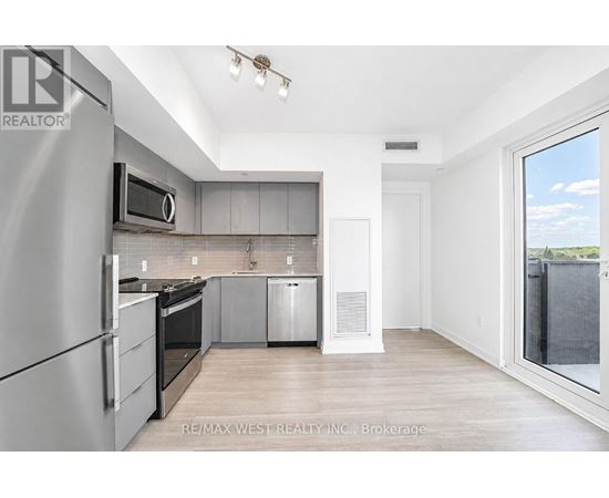 A modern kitchen with stainless steel appliances and wooden flooring.
