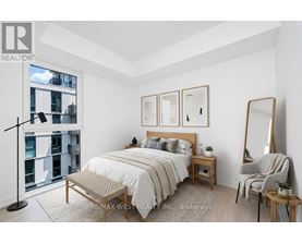 A bedroom with a large bed, a chair, and a mirror.