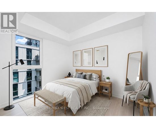 A bedroom with a large bed, a chair, and a mirror.