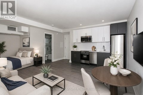 A modern living room with a dining area and kitchen in the background.