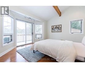 A bedroom with a large bed and a view of a deck through the sliding glass doors.