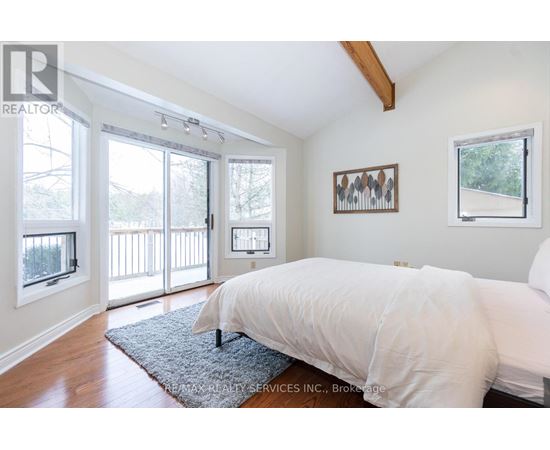 A bedroom with a large bed and a view of a deck through the sliding glass doors.