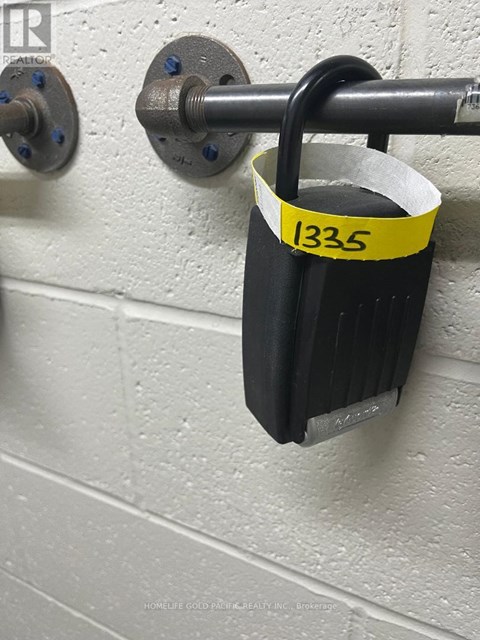 A black padlock with the number 1335 on a yellow tag is attached to a metal rod.