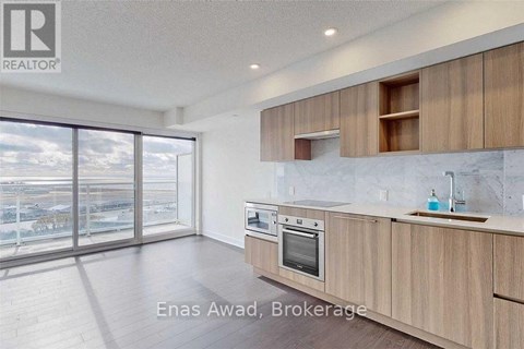 A modern kitchen with wooden cabinets and a marble countertop.