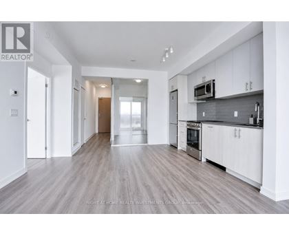 A spacious kitchen with white cabinets and a grey backsplash.