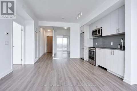 A spacious kitchen with white cabinets and a grey backsplash.