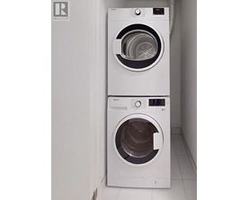 Two white front loading washing machines in a laundry room.