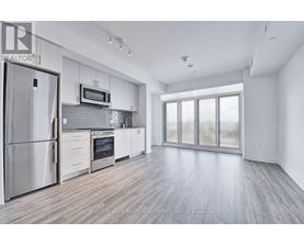 A modern kitchen with stainless steel appliances and wooden flooring.