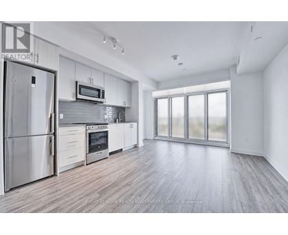 A modern kitchen with stainless steel appliances and wooden flooring.
