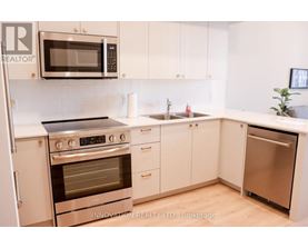 A modern kitchen with white cabinets and stainless steel appliances.