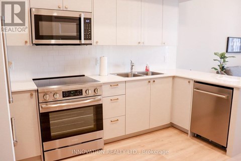 A modern kitchen with white cabinets and stainless steel appliances.