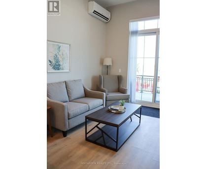 A living room with a grey couch, a coffee table, and a painting on the wall.