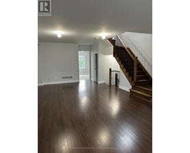 A spacious room with a staircase and wooden flooring.
