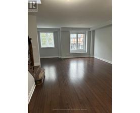 A room with wooden floors and a window overlooking a building.