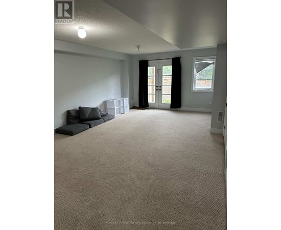 A spacious living room with a grey sofa and a carpeted floor.