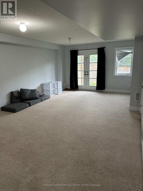 A spacious living room with a grey sofa and a carpeted floor.