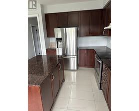 A kitchen with brown cabinets and a stainless steel refrigerator.