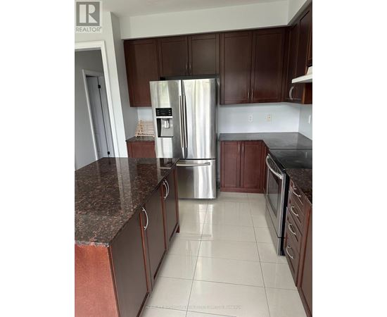 A kitchen with brown cabinets and a stainless steel refrigerator.