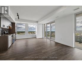 A spacious room with wooden floors and a large window overlooking a body of water.