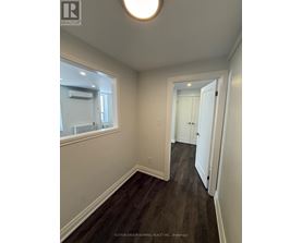 A hallway with wood floors and white walls.