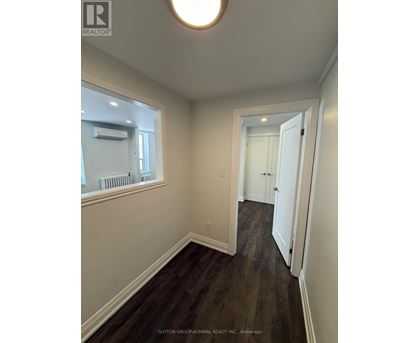 A hallway with wood floors and white walls.
