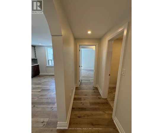 A long hallway with wood floors and white walls.