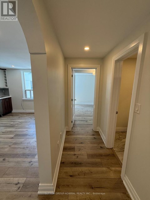 A long hallway with wood floors and white walls.