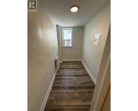 A hallway with wood flooring and white walls.