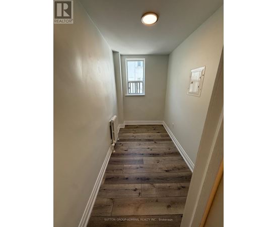 A hallway with wood flooring and white walls.