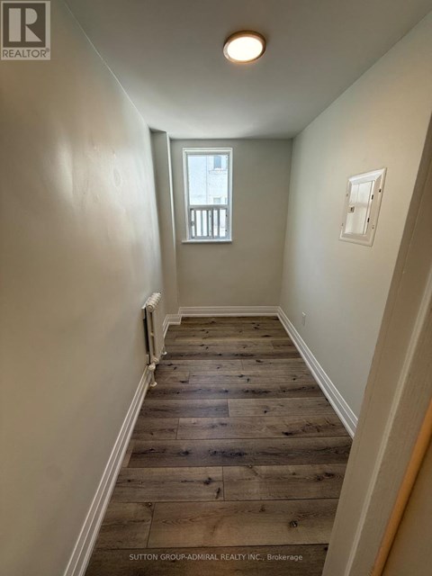 A hallway with wood flooring and white walls.