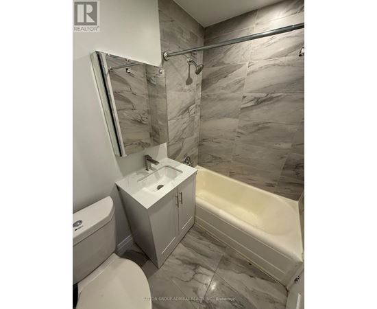 A bathroom with a marble tile wall and a white sink.