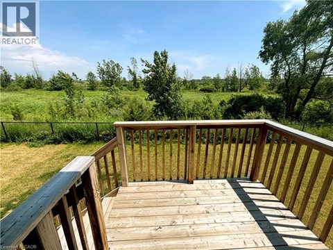 A wooden deck overlooks a grassy field.