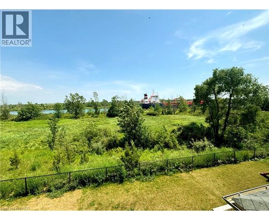A lush green field with a fence and a building in the distance.