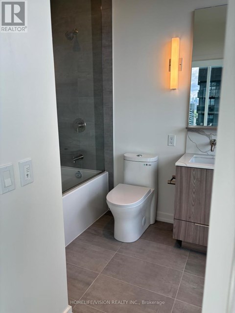 A white toilet sits in a bathroom with a glass shower door.