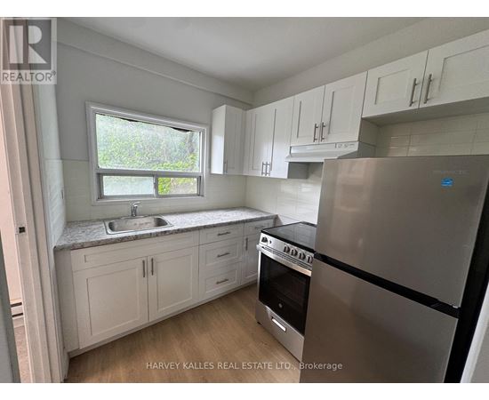 A kitchen with white cabinets and a stainless steel refrigerator.