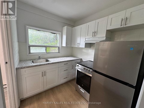 A kitchen with white cabinets and a stainless steel refrigerator.