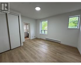 A spacious room with wooden flooring and white walls.