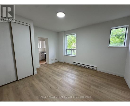 A spacious room with wooden flooring and white walls.