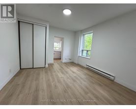 A room with wooden flooring and a window with a view of trees.