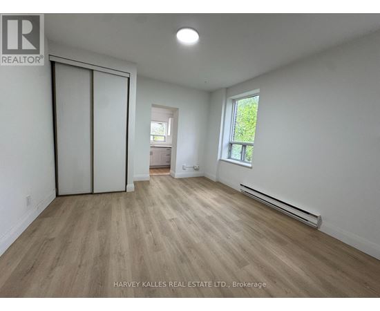 A room with wooden flooring and a window with a view of trees.