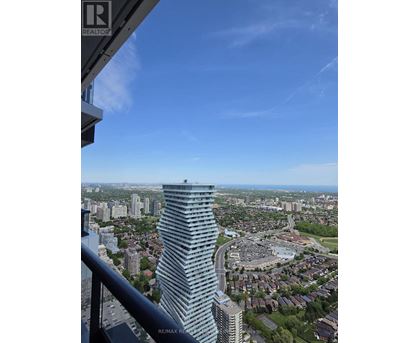 A tall building with many windows stands out in a cityscape.