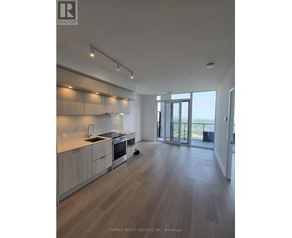 A modern kitchen with wooden floors and a large window.